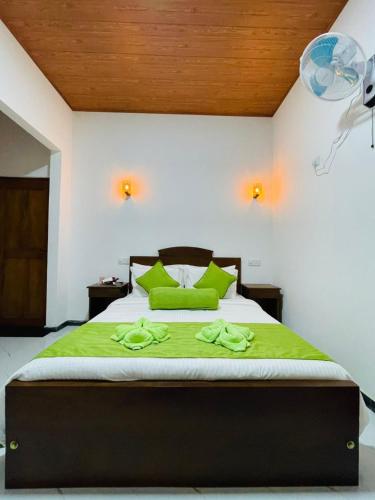 a bedroom with a large bed with green pillows at Erene Inn in Ella