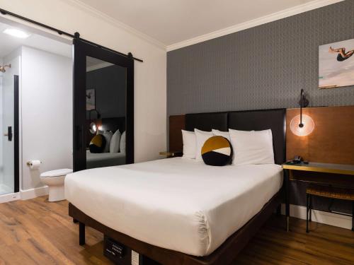 a bedroom with a large white bed and a mirror at Hotel Stratford San Francisco - Handwritten Collection in San Francisco