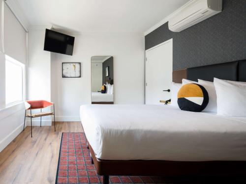 a bedroom with a large white bed and a television at Hotel Stratford San Francisco - Handwritten Collection in San Francisco