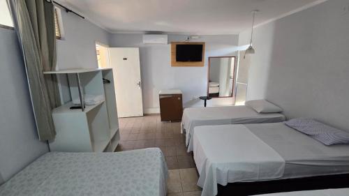 a hotel room with two beds and a mirror at Hotel Pousada Aeroporto in Goiânia
