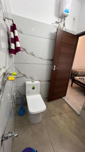 a bathroom with a toilet and a brown door at Little Chandhana Guest House in Kottayam