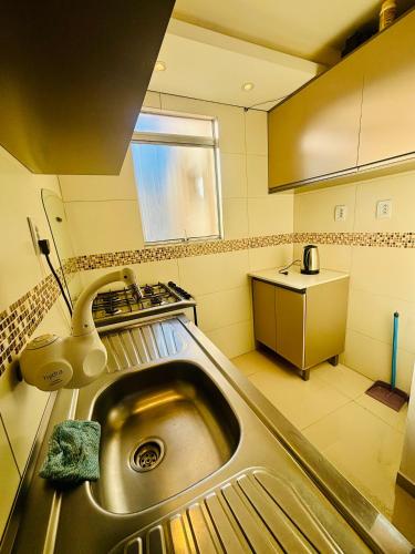 佩洛塔斯Apartamento pelotas的厨房里有水槽和炉灶。