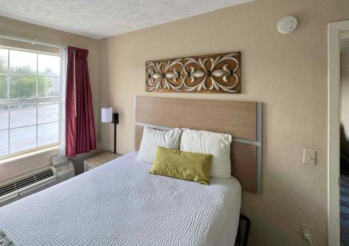 a bedroom with a large white bed with a wooden headboard at Mountain Aire Inn Sevierville - Pigeon Forge in Sevierville