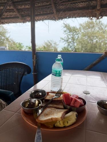 a plate of food with a bottle of water and fruit at Sri Murugan Beach Paradise Hotel in Mahabalipuram