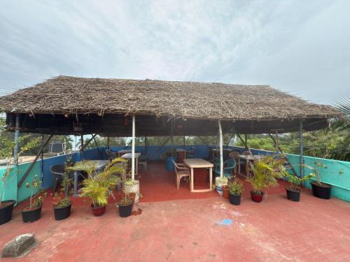 a patio with a large straw umbrella and plants at Sri Murugan Beach Paradise Hotel in Mahabalipuram