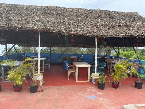 a patio with a large straw umbrella and plants at Sri Murugan Beach Paradise Hotel in Mahabalipuram