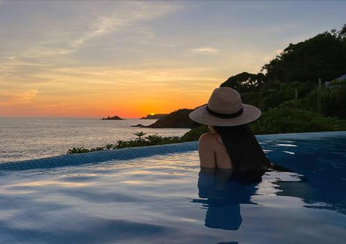a woman sitting in a infinity pool watching the sunset at Oceanfront Villa w Private Jacuzzi & Club Access in Ixtapa