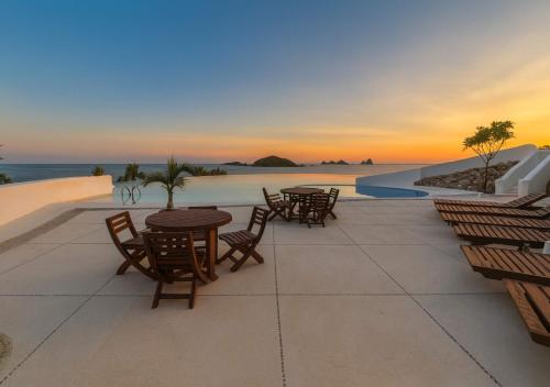 a patio with tables and chairs with a view of the ocean at Oceanfront Villa w Private Jacuzzi & Club Access in Ixtapa