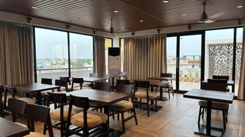 a restaurant with tables and chairs and large windows at Sanguine Varanasi in Varanasi