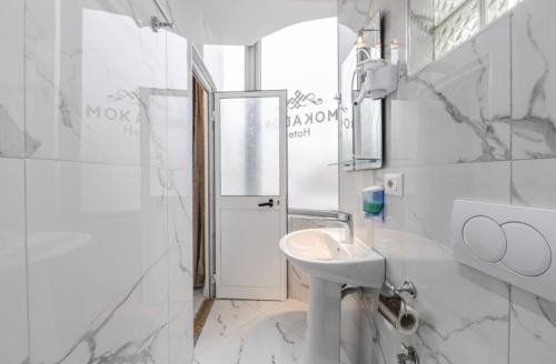 Un baño blanco con lavabo y espejo. en Bar Hotel Mokador, en Shkodër