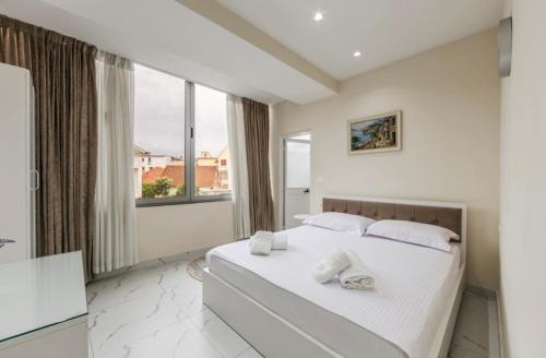 a white bedroom with a large bed with towels on it at Bar Hotel Mokador in Shkodër