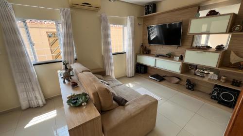 Una sala de estar con un sofá y un televisor de pantalla plana. en Casa com piscina e churrasqueira conforto e lazer garantido, en Manaus