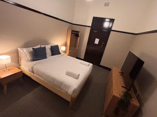 a bedroom with a bed and a television in it at Strathfield Hotel in Sydney