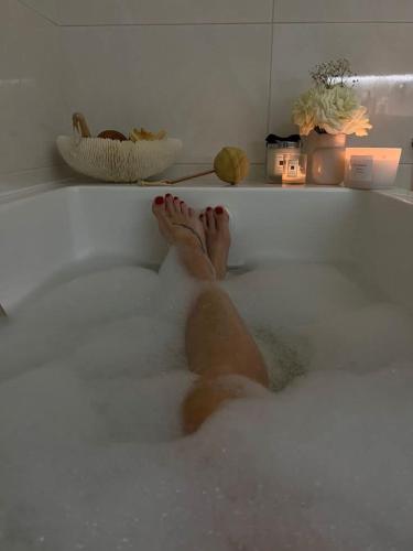 a persons feet in a bath tub filled with foam at Pousada residencial in Curvelo