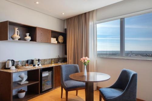 a living room with a table and chairs and a kitchen at Windsor Brasilia Hotel in Brasilia