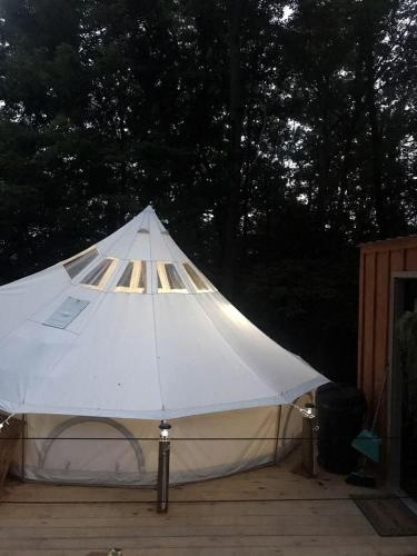 a white tent is set up on a deck at A Truly Glamping Experience in this Beautiful Tent in Victor, West Virginia in Victor