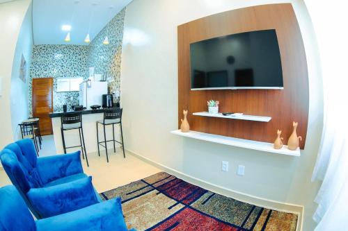 un salon avec des chaises bleues et une télévision sur un mur dans l'établissement Conforto em Boa Vista com varanda e garagem privado, à Boa Vista