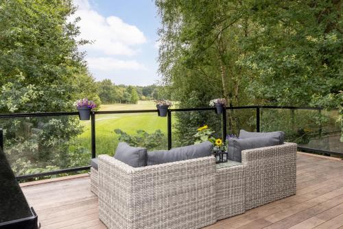 a patio with two wicker chairs on a deck at Onder het dak van Brabant in Mierlo