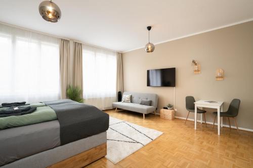 a bedroom with a bed and a tv and a couch at Boho Living Altstadt Suites - Free Parking by HERO HOMES Graz in Graz