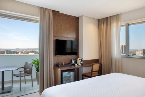 a hotel room with a bed and a desk with a television at Windsor Brasilia Hotel in Brasilia