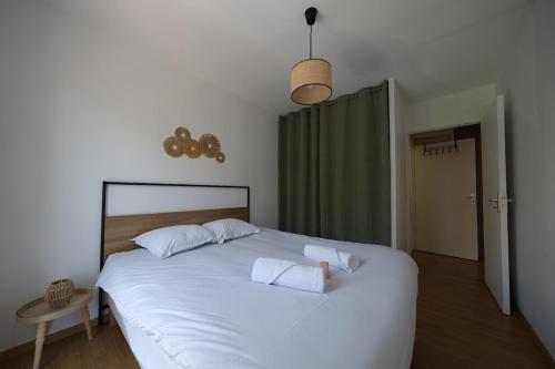 a bedroom with a white bed with two white pillows at Lumineux T3 - 2 chambres, balcon - proche de Rouen in Le Petit-Quevilly