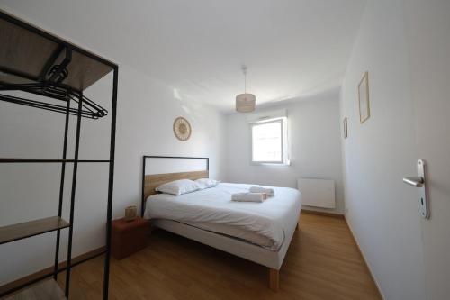 a white bedroom with a bed and a window at Lumineux T3 - 2 chambres, balcon - proche de Rouen in Le Petit-Quevilly