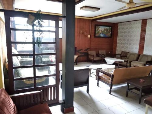 a restaurant with couches and tables and a large window at Hotel Budi Famili Budget Syariah in Ciamis