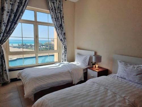 Una habitación de hotel con dos camas y una ventana. en شقة منتزة المارينا, en King Abdullah Economic City