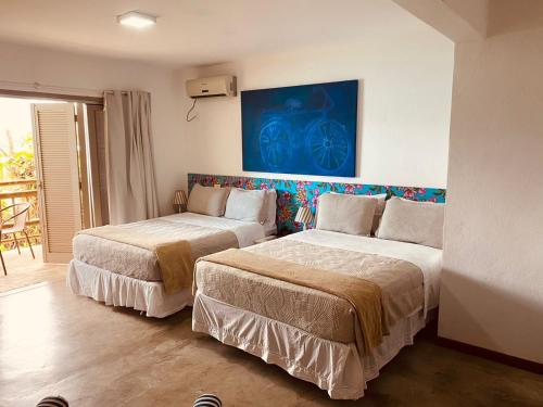 a bedroom with two beds and a blue painting on the wall at Hotel Boutique Ananas in Ilhabela