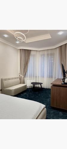 アルマトイにあるRadamis Hotelのベッドとソファとテーブルがあるホテルの部屋