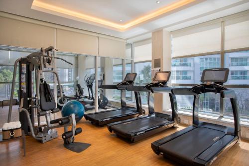 a gym with treadmills and ellipticals in a room with windows at Windsor Brasilia Hotel in Brasilia