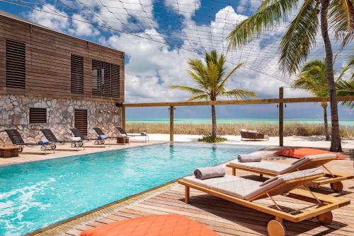 a pool with chaise lounges and chairs next to the ocean at Spectacular spacious 8 bedroom family villa in Providenciales