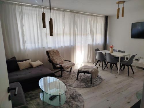 Una sala de estar con un sofá, una mesa y sillas. en Apartmán Harmónia, en Mýto pod Ďumbierom