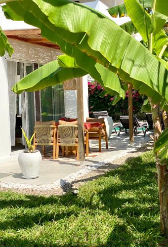 a patio with a table and chairs and a large banana leaf at Luxury Lions Villas Zanzibar - with Private Cook&Infinity Pools in Kiwengwa