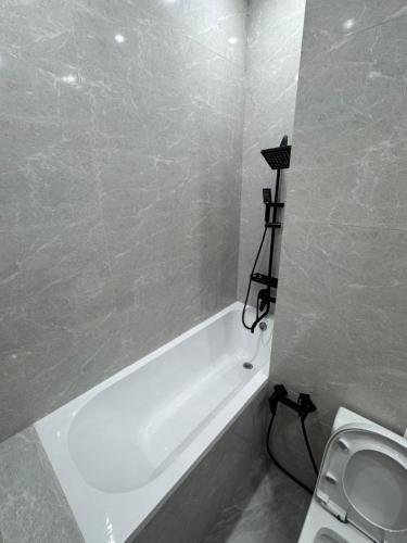 a bathroom with a white tub and a toilet at Уютная студия в жк Four Seasons in Zhezdi