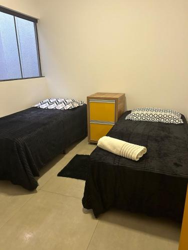 a room with two beds and a dresser in it at Linda casa próximo faculdade UCDB mínimo 2 diarias in Campo Grande