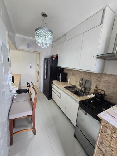 una cucina con mobili bianchi, un tavolo e una stufa di Apartamento de 2 quartos a Belém