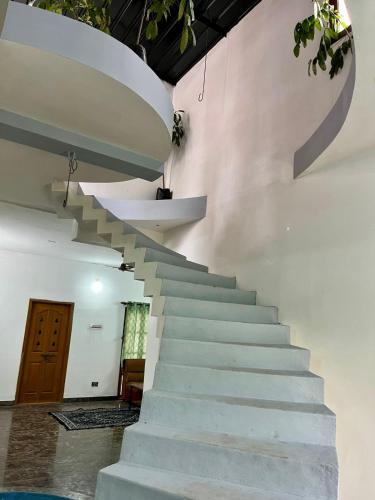 a staircase in a house with a white wall at 2BHK Farm Villa In Kovai Kuttralam Mainroad Near ISHA By Shivalaya in Coimbatore