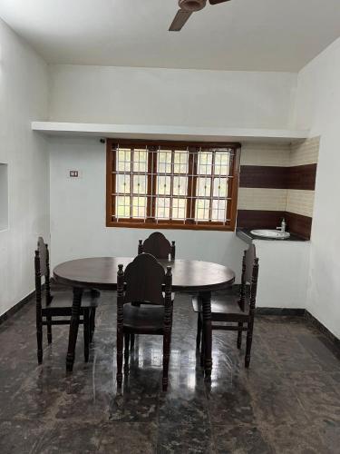 a dining room with two tables and chairs and a window at 2BHK Farm Villa In Kovai Kuttralam Mainroad Near ISHA By Shivalaya in Coimbatore