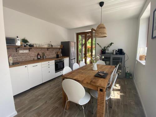a kitchen with a wooden table and white chairs at Berkenye Vendégház Tisza-tó in Abádszalók
