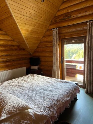 a bedroom with a bed in a log cabin at Casa Brindusa in Poiana Negrii