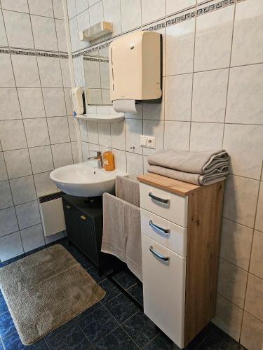 a small bathroom with a sink and a paper towel dispenser at Ferienwohnung Villach Süd in Villach