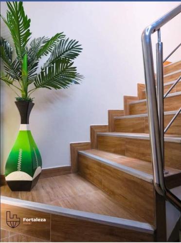 a green vase with a plant in it next to stairs at Hotel Fortaleza in Chasquitambo