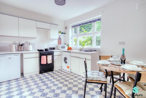 a kitchen with a table and a kitchen with white cabinets at Flat By Stay Aura Short Term Lets Newcastle With Free WiFi & Parking in Kenton