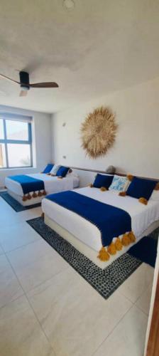 three beds in a room with blue and white at Beachfront White Villa in Playa Blanca in Zihuatanejo