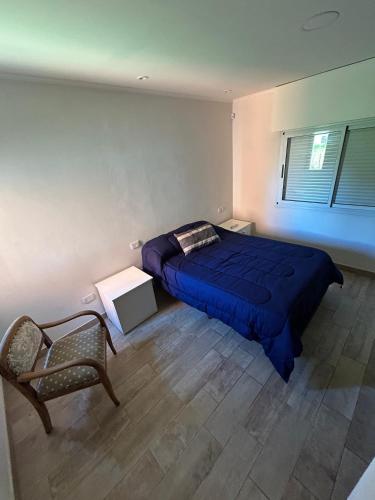 Un dormitorio con una cama azul y una silla. en Quinta Los Cisnes Junin, en Junín
