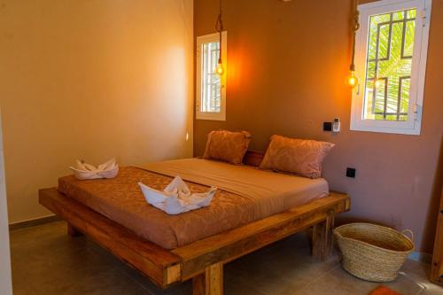 a bed in a room with two white flowers on it at Mayssa Villa in Paje