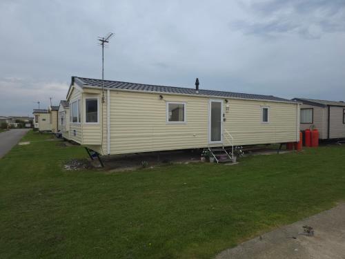 una pequeña casa amarilla al lado de un patio en The Retreat Lido Beach - Lido Beach Prestatyn, en Prestatyn