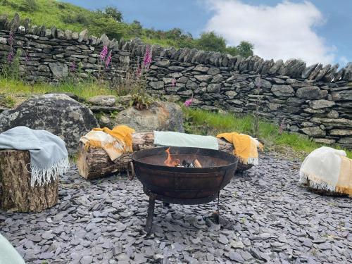 a fire pit in front of a stone wall at 4 Bed in Betws y coed 52111 in Capel Garmon