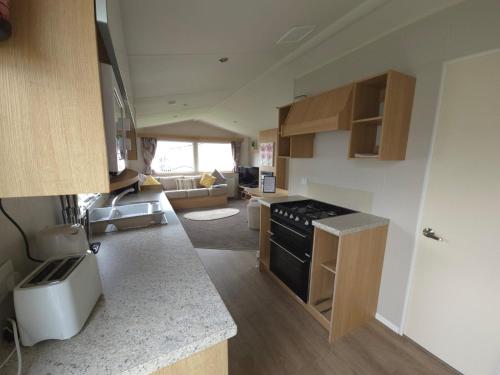 a kitchen with a stove and a living room at The Retreat Vacation in Kinmel Bay